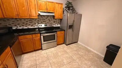a kitchen with wooden cabinets and a stainless steel refrigerator at L12 Private Room with Smart TV Near Everything in Orlando