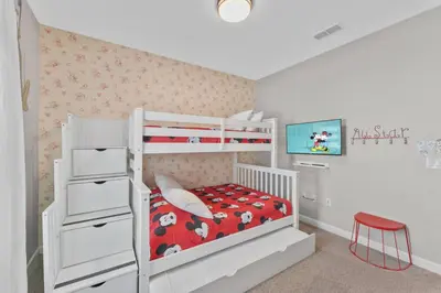 a white bedroom with a bunk bed with a red comforter at 4824 Resort Pool House Disney Universal Orlando in Kissimmee