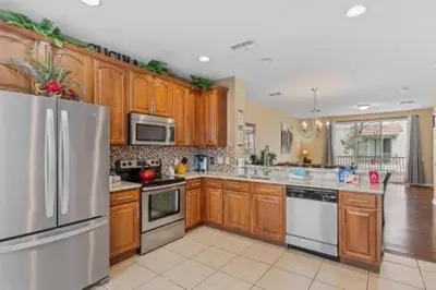 a kitchen with wooden cabinets and a stainless steel refrigerator at 3-Story sanctuary Condo in the heart of Orlando85 in Orlando