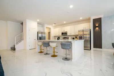 a kitchen with white cabinets and blue bar stools at Stunning Masterpiece 15 ensuites in Kissimmee