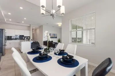 a kitchen and dining room with a white table and chairs at Gorgeous Waterview ,Top Floor, 2Bd Condo, Storey Lake Resort in Kissimmee