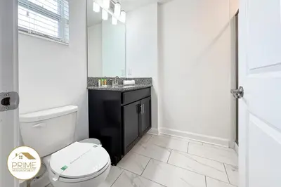 a white bathroom with a toilet and a sink at New Themed Rooms5BR Near AttractionsResort in Kissimmee