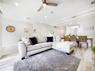 a living room with a white couch and a dining room at Gated 3BR 3BA Townhome Near Disney w Pool and Gym in Orlando