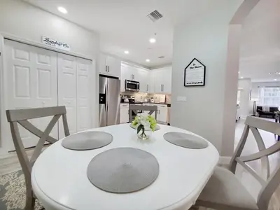 a white kitchen with a table and two chairs at Gated 3BR 3BA Townhome Near Disney w Pool and Gym in Orlando