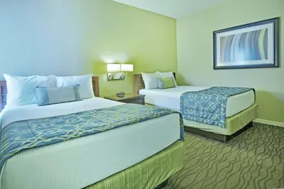 a hotel room with two beds and two tables at Wyndham Star Island Resort 2BR Apartment with Resort Access in Kissimmee