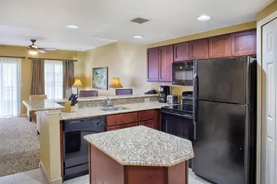 a kitchen with wooden cabinets and a stainless steel refrigerator at Wyndham Cypress Palms 2BR Apartment with Resort Access in Kissimmee