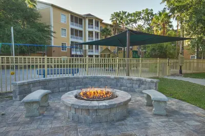 a fire pit with benches and an umbrella at Wyndham Cypress Palms 2BR Apartment with Resort Access in Kissimmee
