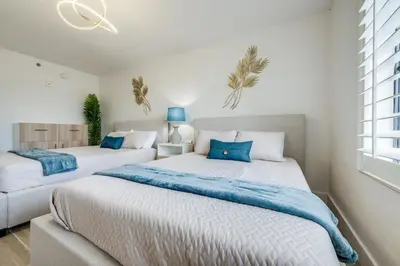 two beds in a bedroom with blue pillows at Rental near Epic and Universal, free parking in Orlando