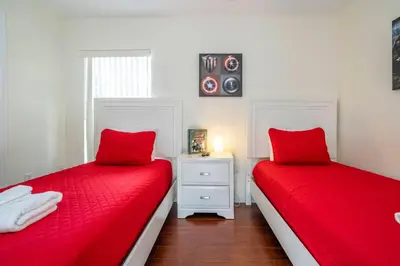two beds with red covers in a room at Amazing 6 bedrooms with pool in Kissimmee