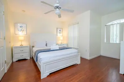 a white bedroom with a bed and a ceiling fan at Amazing 6 bedrooms with pool in Kissimmee