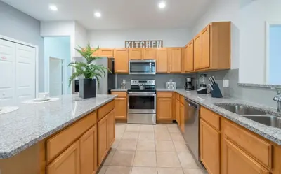 a large kitchen with wooden cabinets and stainless steel appliances at Family Nest 4-Bedroom Home Near Disney World in Kissimmee