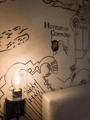 a lamp on a table next to a wall with drawings at Harry Potter Suite near Epic & Universal in Orlando