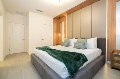 a bedroom with a large bed with a green blanket on it at Paradiso Grande 6 bedroom New Home - 10377 in Orlando