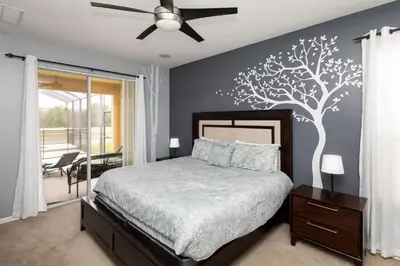 a bedroom with a bed with a tree mural on the wall at Be Our Guest at Emerald Island in Kissimmee