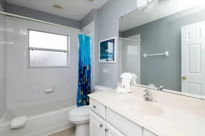 a bathroom with a sink and a toilet and a mirror at Be Our Guest at Emerald Island in Kissimmee