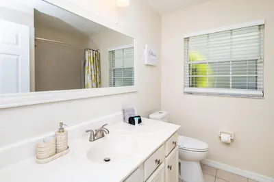 a white bathroom with a sink and a mirror at Beachy Retreat in Orlando