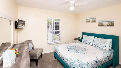 a bedroom with a bed and a chair and a window at Beachy Retreat in Orlando