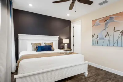 a bedroom with a white bed with a blue pillow at Caribbean Dreamin - Vibrant Margaritaville Resort in Orlando