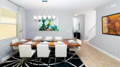 a dining room with a wooden table and white chairs at Casa de Kissimmee Sleeps up to 13 Guests in Kissimmee