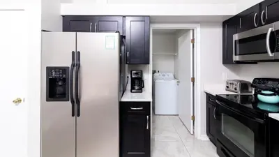 a kitchen with a white refrigerator and black cabinets at Cozy on Cavendish - Themed bedrooms in Kissimmee
