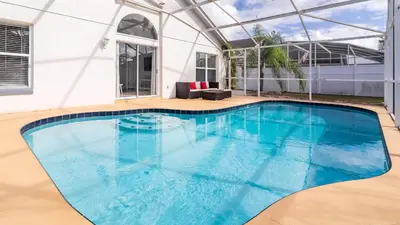 a large swimming pool with blue water in a house at Cozy on Cavendish - Themed bedrooms in Kissimmee
