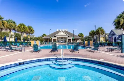 a pool at a resort with chairs and a house at Enchanted At 7 Dwarfs Lane in Kissimmee