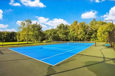 a tennis court with a blue tennis court at Enchanted At 7 Dwarfs Lane in Kissimmee