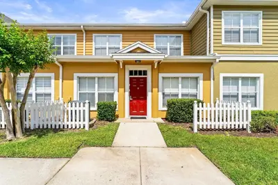 a yellow house with a red door and a white fence at Enchanted At 7 Dwarfs Lane in Kissimmee