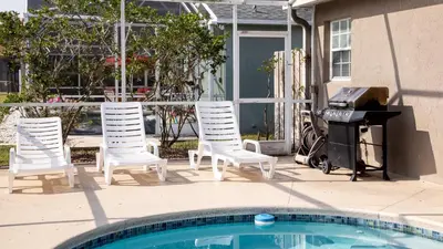 a group of chairs and a grill next to a pool at Wonderland at White Crane - Hot tub & Lake views in Orlando