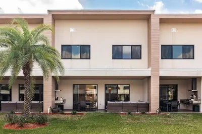 a building with a palm tree in front of it at Villa at Magic Village Resort with Outdoor Oasis in Orlando