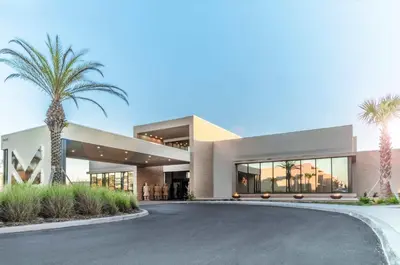 a large building with palm trees in front of it at Villa at Magic Village Resort with Outdoor Oasis in Orlando