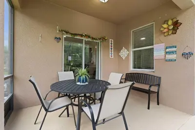 a black table with white chairs and a table with a plant on it at Veranda Sunshine Escape - 5 BDR in Kissimmee