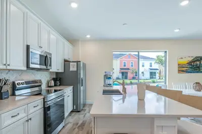 a kitchen with white cabinets and a large window at Turquoise Breeze - Close to Disney in Orlando