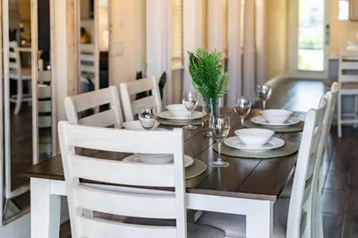 a dining room table with white chairs and a wooden table with glasses at Lafitte's Landing Lakeview Cottage - Lakefront in Orlando