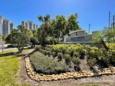 a garden in front of a building with a sign at Lake Views At Blue Heron in Orlando