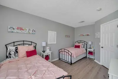 a bedroom with two beds with pink comforter at Create Lasting Magical Memories Resort Home for 8 in Kissimmee