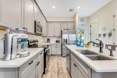 a kitchen with white cabinets and stainless steel appliances at The Sea Shelter - Sunny 4 BDR in Margaritaville in Orlando