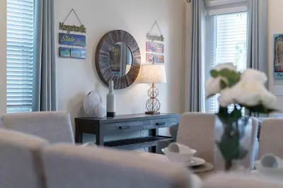 a living room with a table and a mirror at The Sea Shelter - Sunny 4 BDR in Margaritaville in Orlando