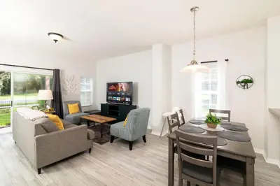 a living room with a table and a dining room at The Emerald Cove - Best Spot in Kissimmee in Kissimmee