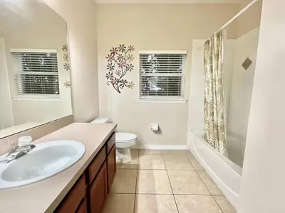 a bathroom with a sink and a toilet and windows at Marcellas Villa At Acadia Estates in Orlando