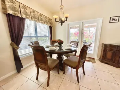 a dining room with a table and chairs and windows at Marcellas Villa At Acadia Estates in Orlando