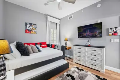 a bedroom with a bed and a tv on the wall at Minutes to Magic in Orlando