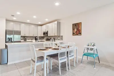 a kitchen and dining room with a white table and chairs at Once Upon a Stay in Kissimmee