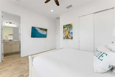 a white bedroom with a large bed and a mirror at Parrot Paradise Escape for 8 in Orlando