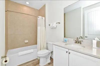 a white bathroom with a toilet and a sink at Pistachio Palace - Sleeps 10 in Orlando
