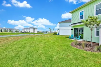 a house with a grass yard next to a building at Pistachio Palace - Sleeps 10 in Orlando