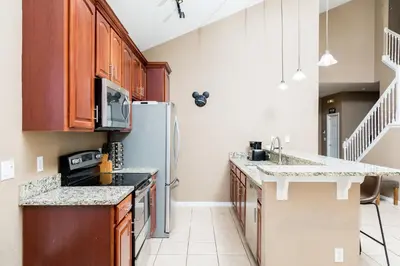 a kitchen with wooden cabinets and a refrigerator at Serendipity at Acadia - Family getaway in Orlando