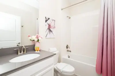 a bathroom with a sink and a pink shower curtain at Storeybook Escape - Sleeps 11 in Kissimmee