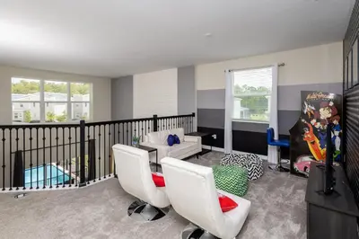 a living room with white chairs and a balcony at Storeybook Escape - Sleeps 11 in Kissimmee