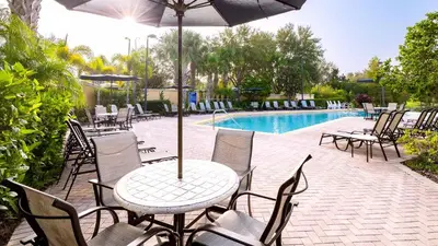 a table and chairs with an umbrella next to a pool at Sunny Haven At Caribe Cove in Kissimmee